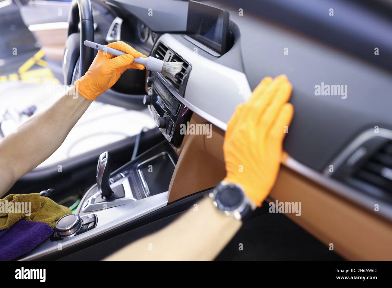 Master cleans ventilation system in car with brush closeup Stock Photo
