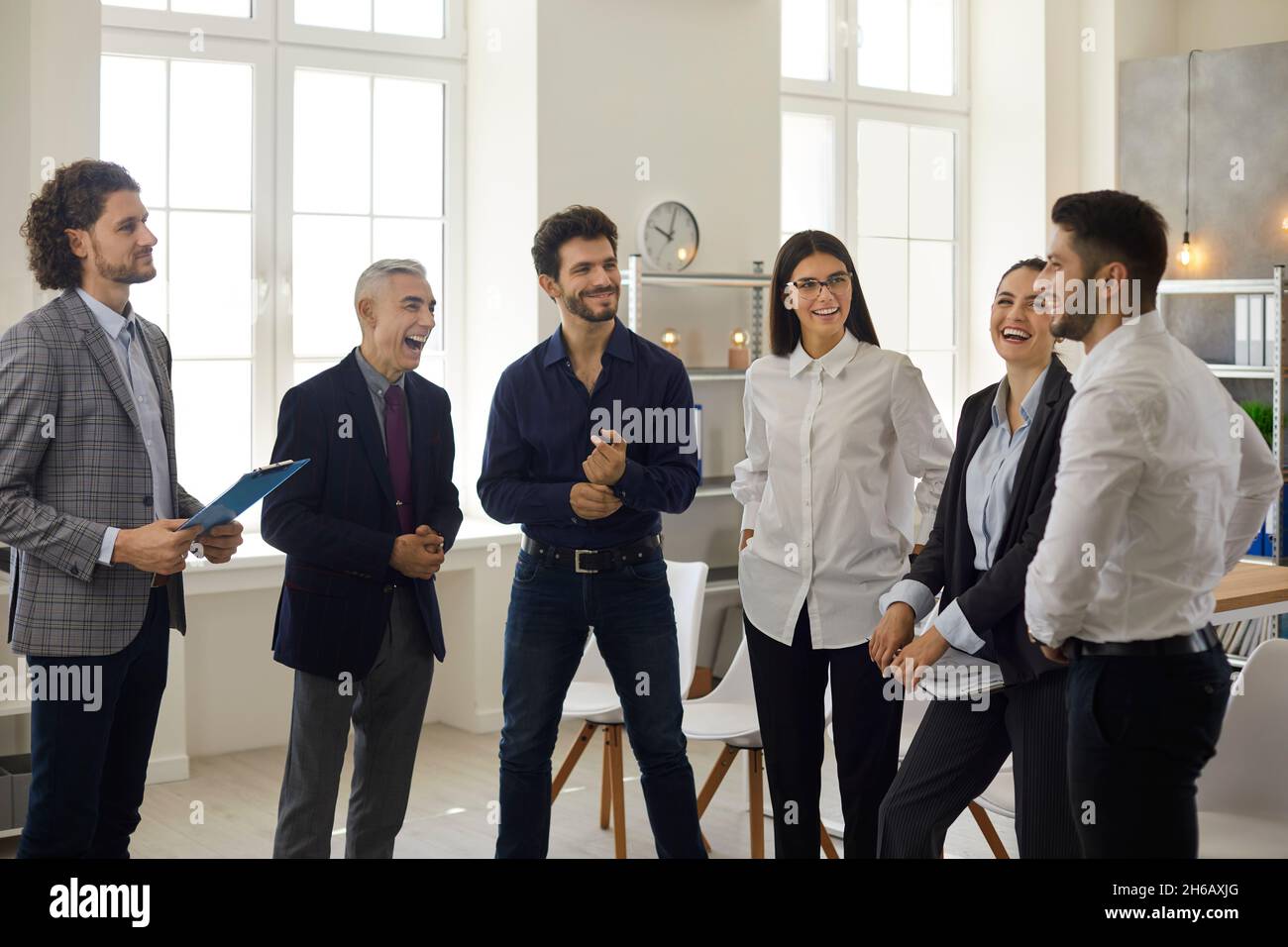 Happy young business team having a fun conversation with a mature manager in the office. Stock Photo