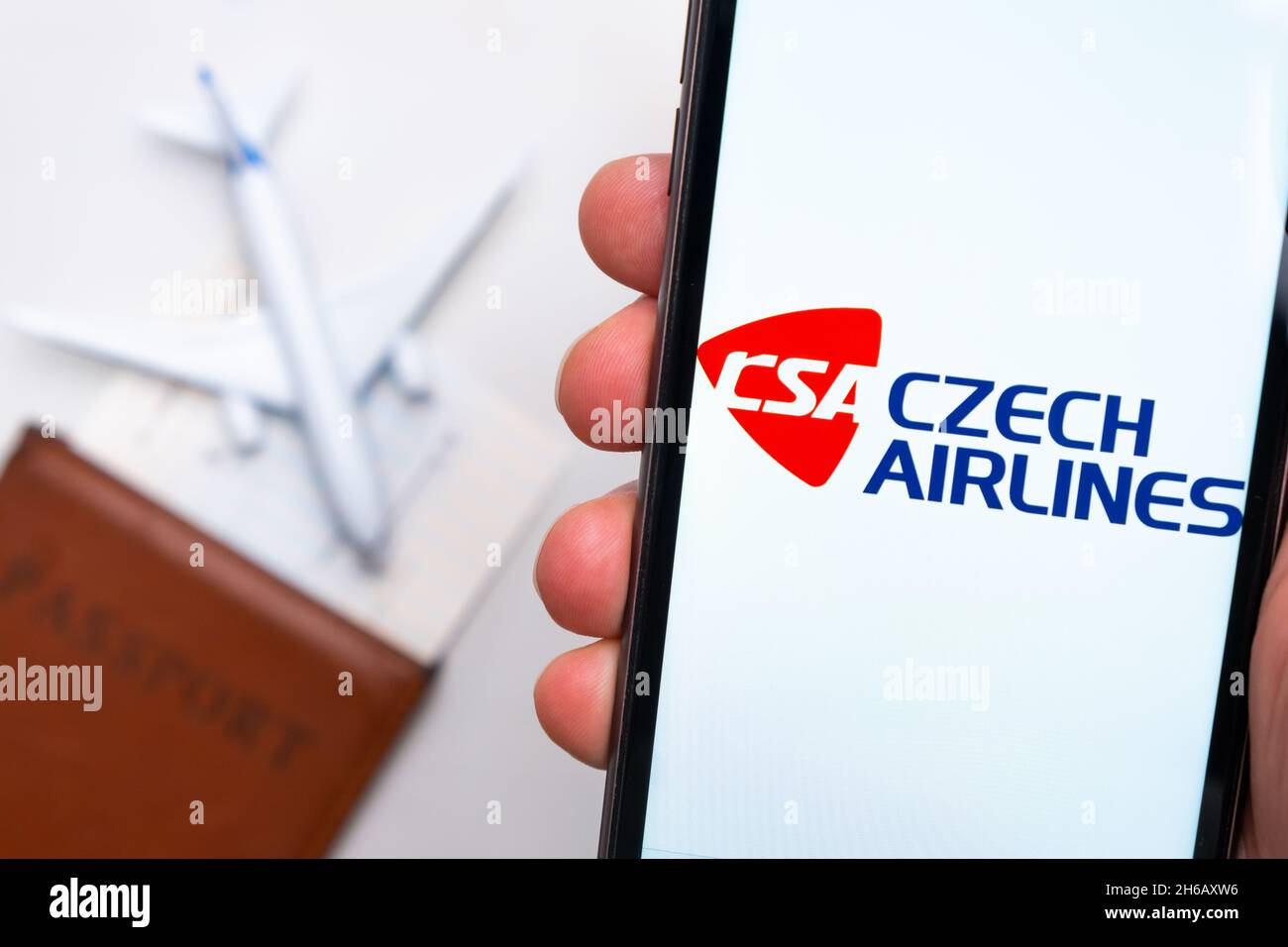 CSA Czech Airlines . A mobile phone and CSA Czech Airlines application in mans hand. There is a passport and a plane on a white table. November 2021, San Francisco, USA Stock Photo