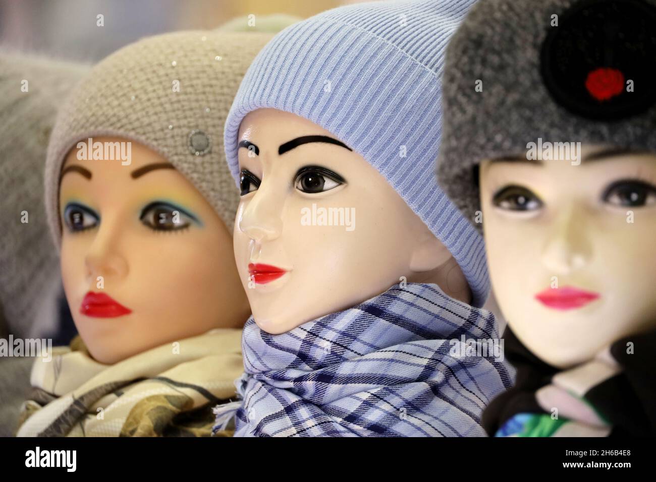 Female warm knitted hats and neckerchiefs on mannequins. Winter clothing store, woolen caps on sale Stock Photo