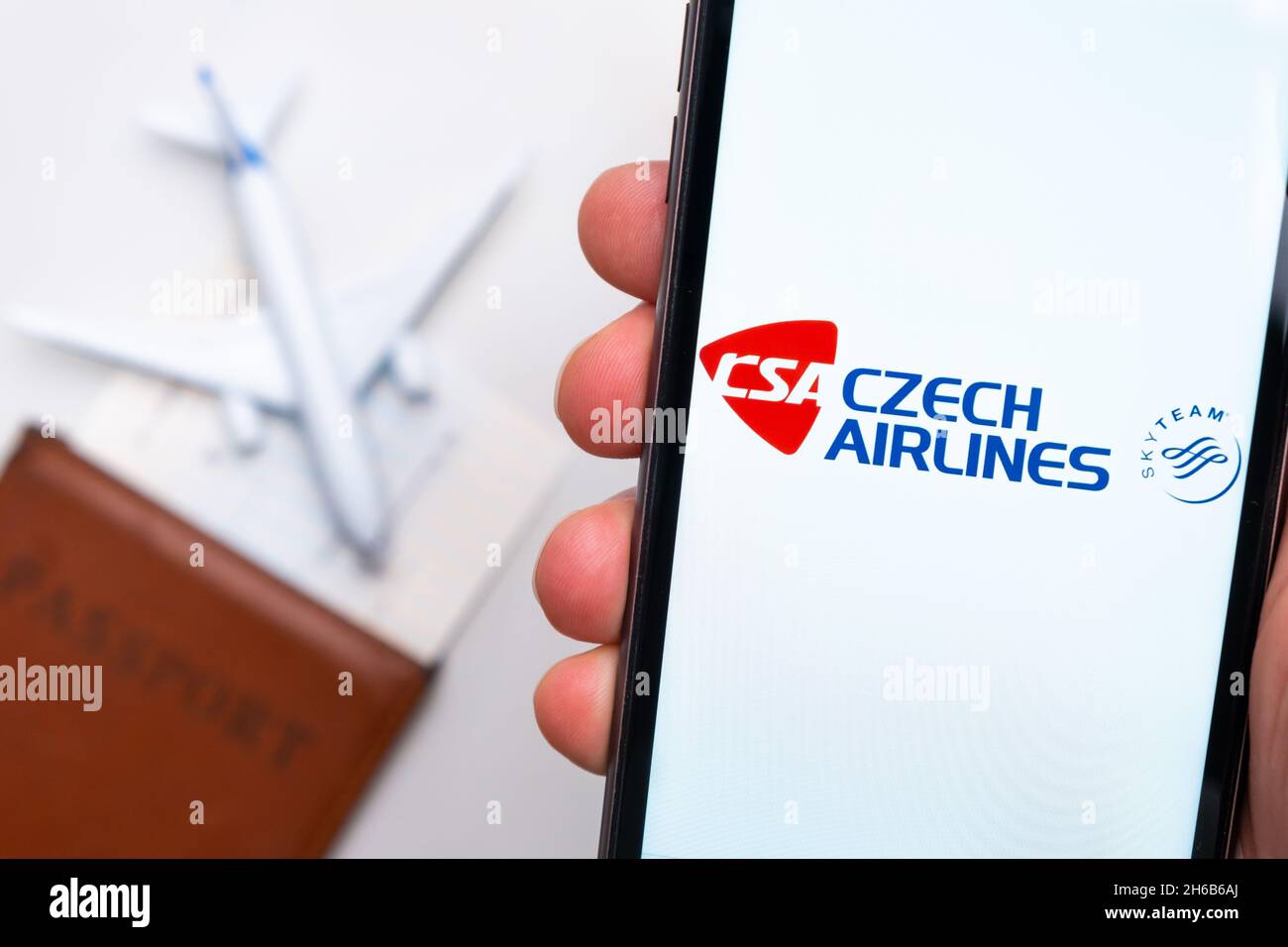 CSA Czech Airlines . A mobile phone and CSA Czech Airlines application in mans hand. There is a passport and a plane on a white table. November 2021, San Francisco, USA Stock Photo