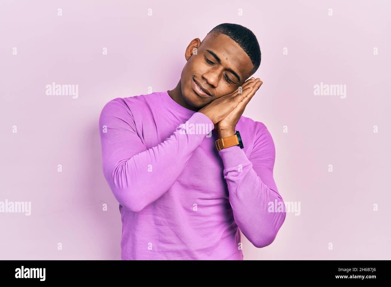 Young black man wearing casual pink sweater sleeping tired dreaming and ...