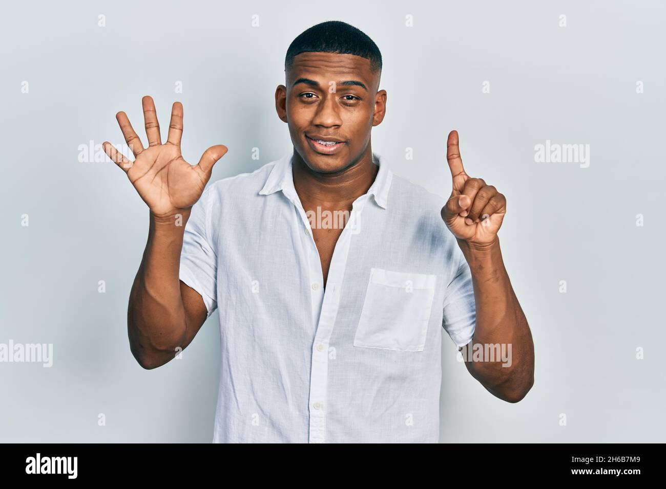 Young black man wearing casual white shirt showing and pointing up with ...