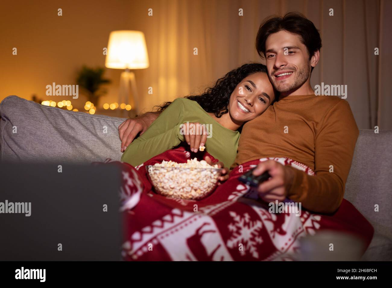 Cheerful Couple Watching TV On Christmas Eve, Switching Channels With