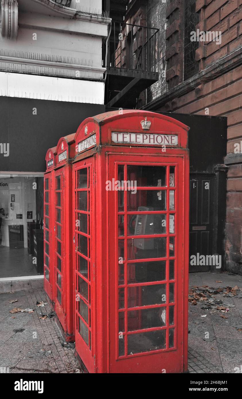 Three Old Red Communication Telephone Boxes in a Line on an Urban Street in the UK Stock Photo