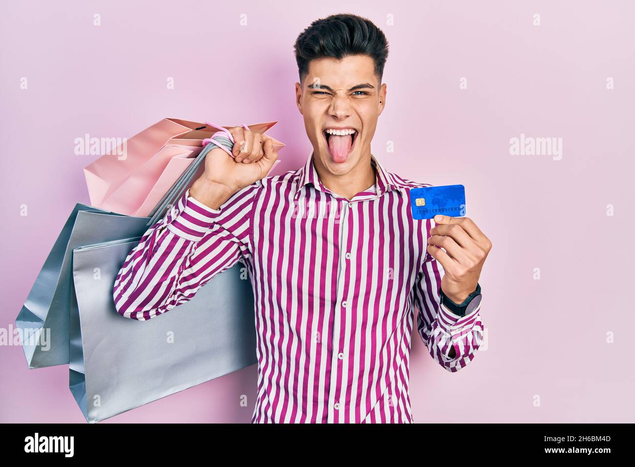 Young hispanic man holding shopping bags and credit card sticking