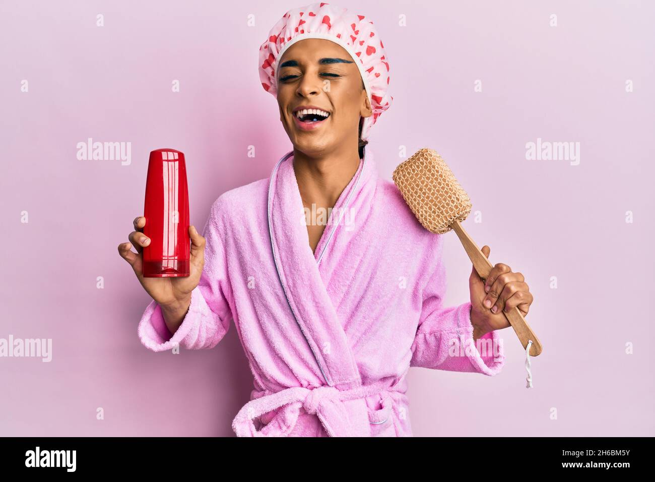 Hispanic man wearing make up wearing shower cap holding sponge and shampoo  smiling and laughing hard out loud because funny crazy joke Stock Photo -  Alamy