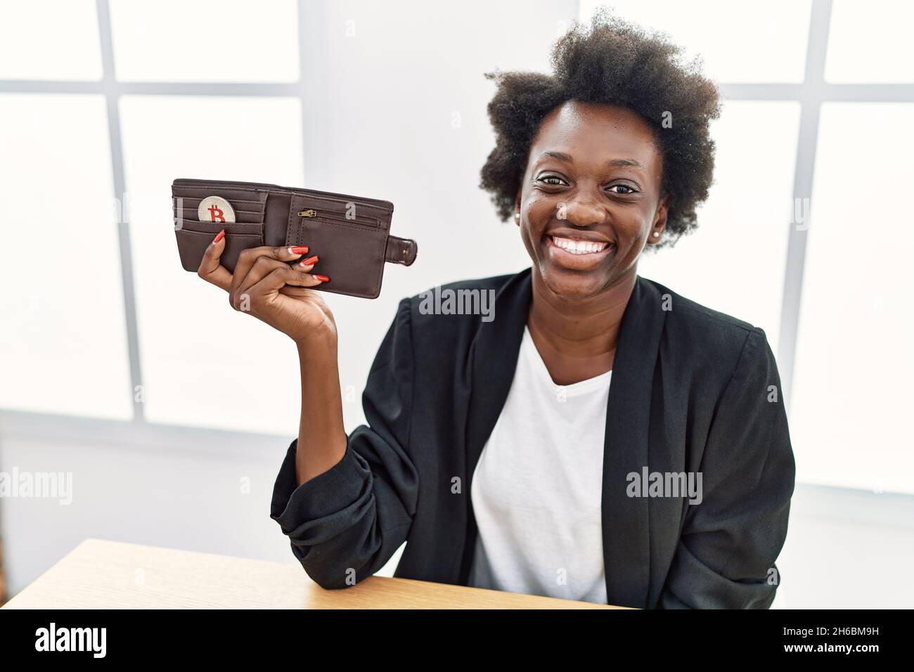 African young woman holding wallet with virtual currency bitcoin looking  positive and happy standing and smiling with a confident smile showing  teeth Stock Photo - Alamy