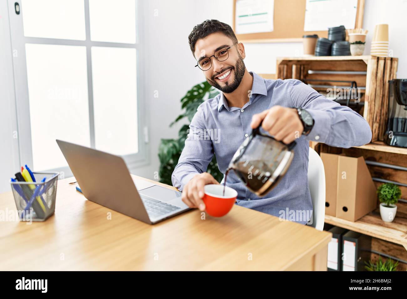 Young arab man smiling confident drinking coffee working at office Stock Photo
