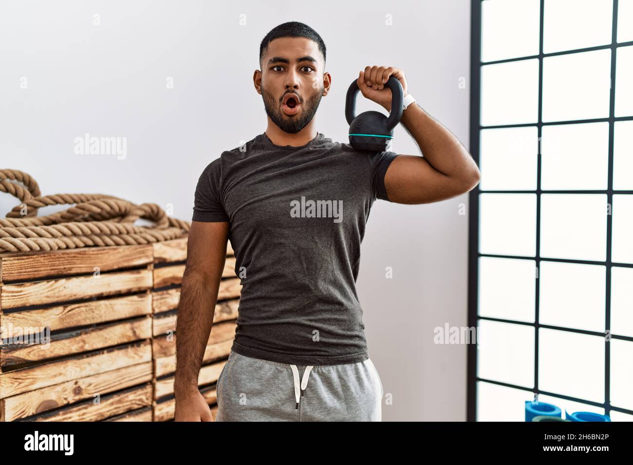 Young indian man wearing sportswear using dumbbells scared and amazed with  open mouth for surprise, disbelief face Stock Photo - Alamy
