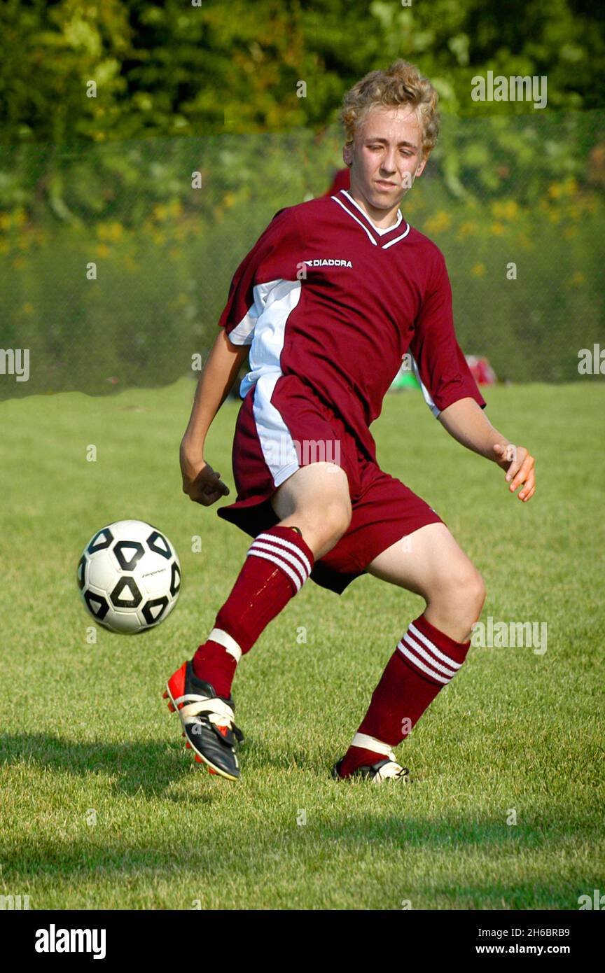 Boys High School American Soccer football action with boy kicking soccer ball Stock Photo
