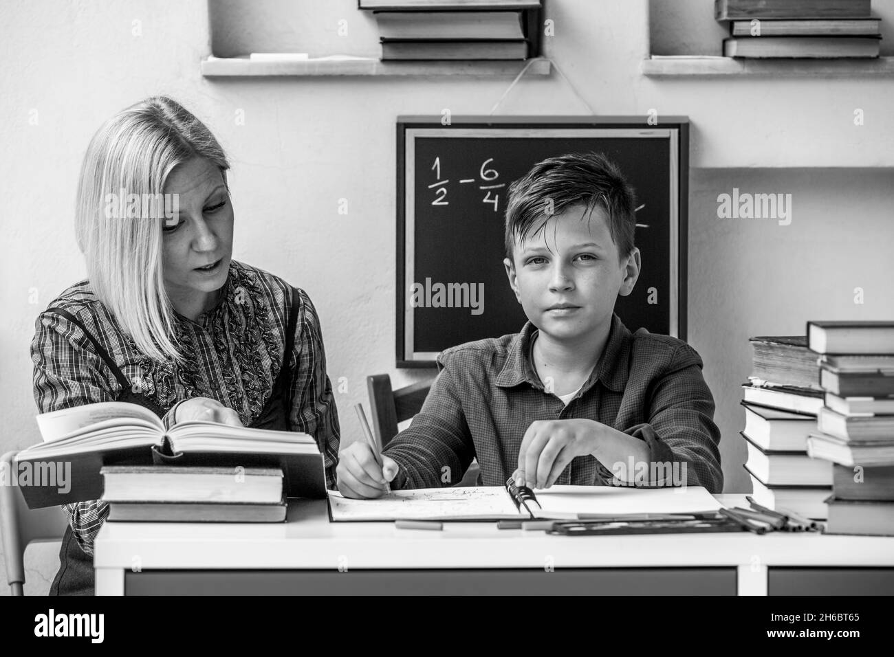 Elementary school boy doing homework with teacher. Black and white photo. Stock Photo