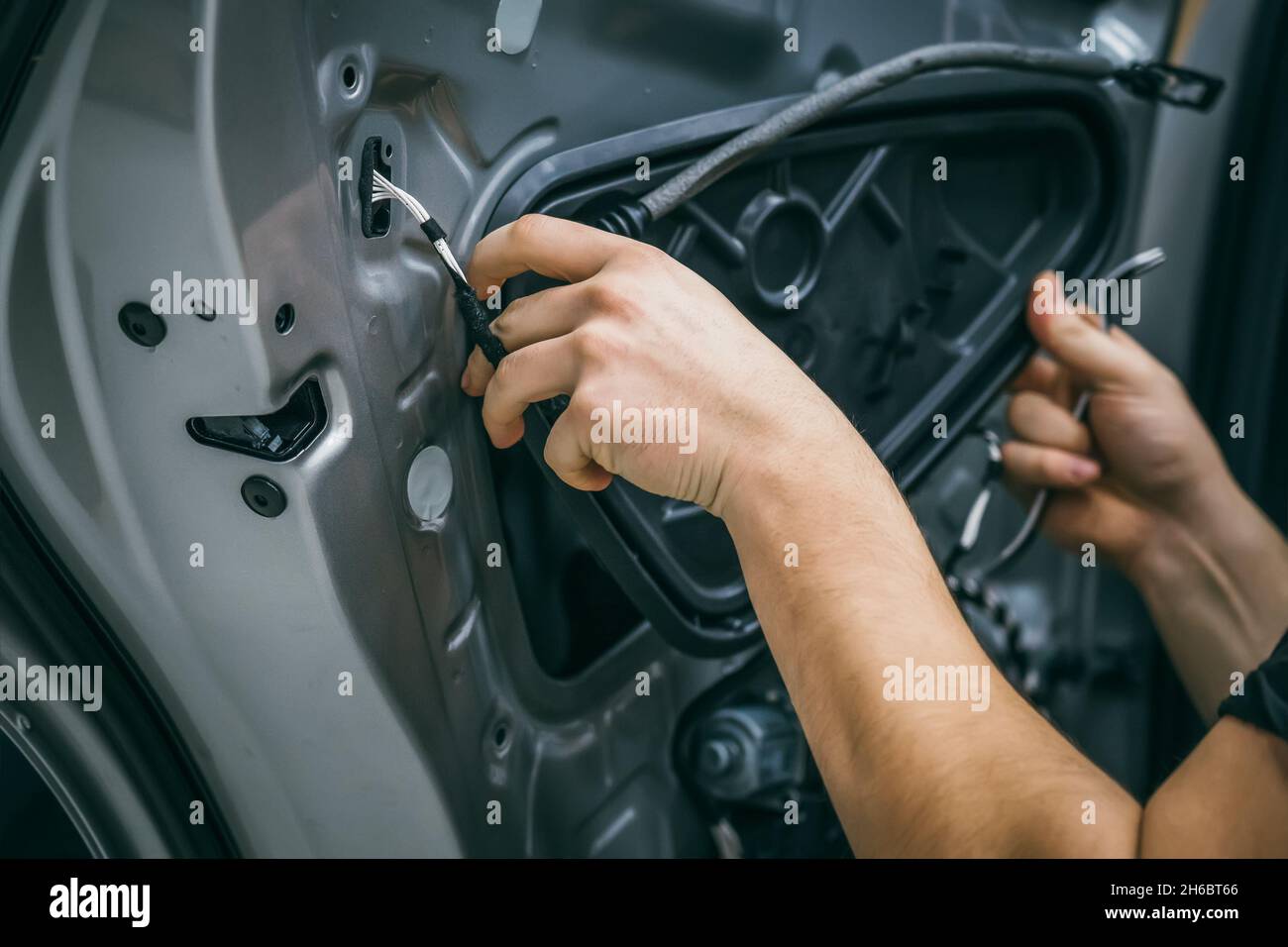 Auto service worker disassembles car door for repair, restoration, tuning car sound or installing noise insulation or soundproofing. Stock Photo