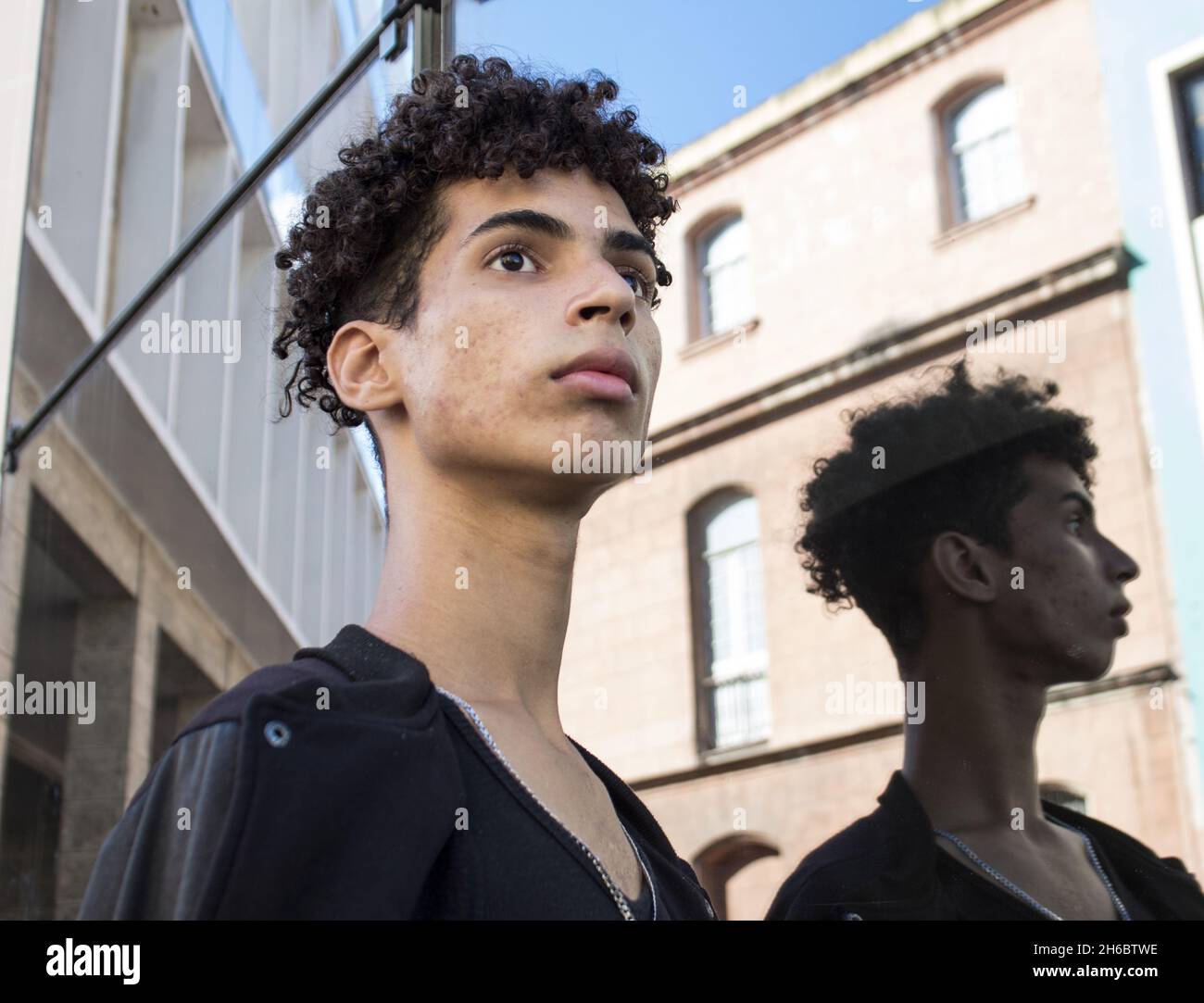 A young curly-haired Hispanic male looking aside in the streets of Old  Havana, Cuba Stock Photo - Alamy