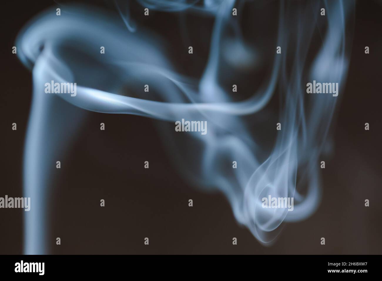 Smoke clouds swirling in blue light against a dark background Stock