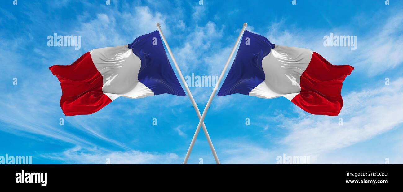 two crossed flags of France waving in the wind at cloudy sky ...
