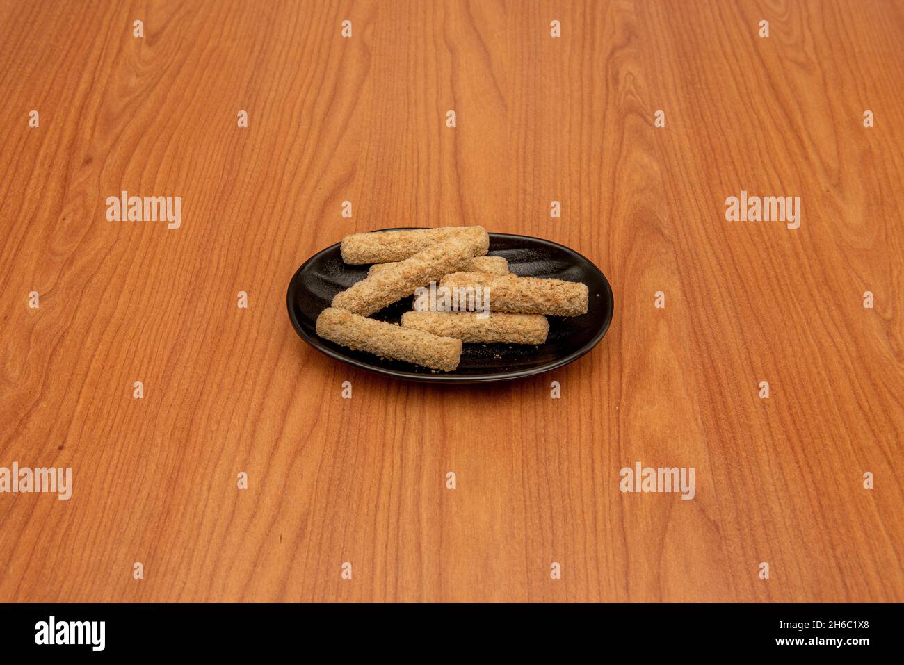 Battered mozzarella sticks on black plate Stock Photo