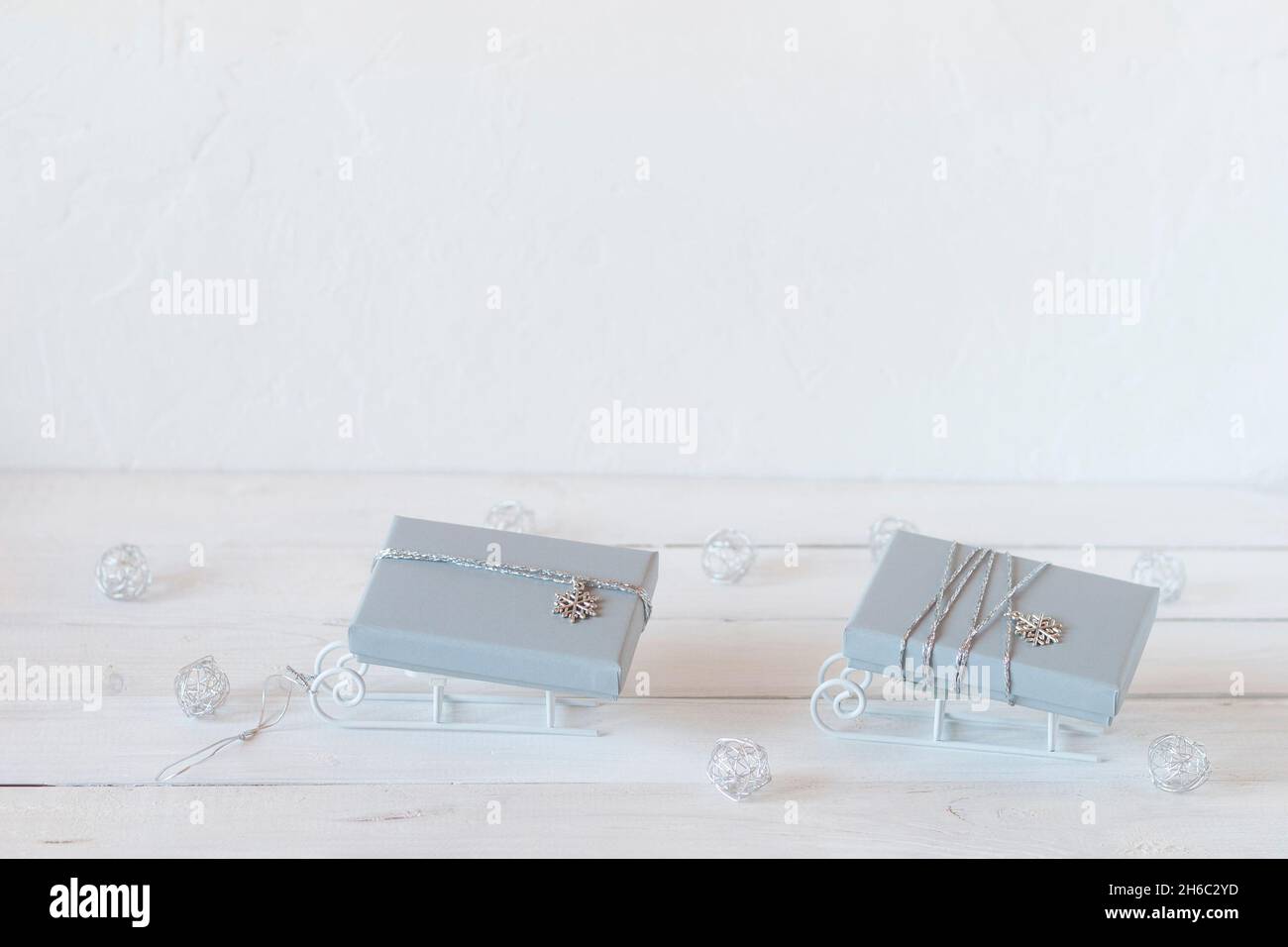 tiny decorative sleds with grey Christmas gift boxes, white, grey and silver colors, copy space, idea for Christmas card Stock Photo