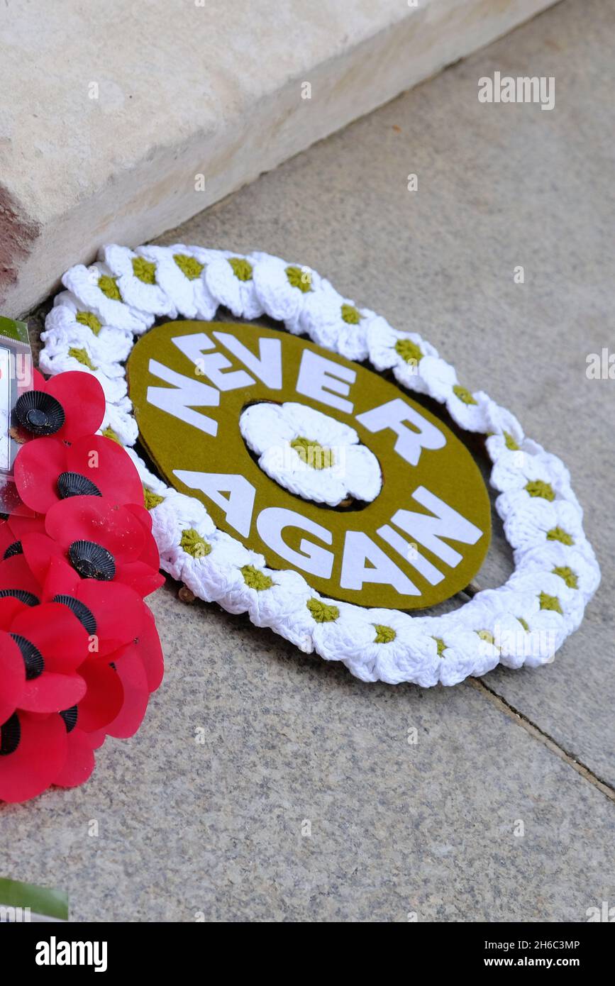 London, UK. A white poppy wreath with the words: 'Never Again', placed alongside a traditional wreath placed at the Cenotaph on Remembrance Day. Stock Photo