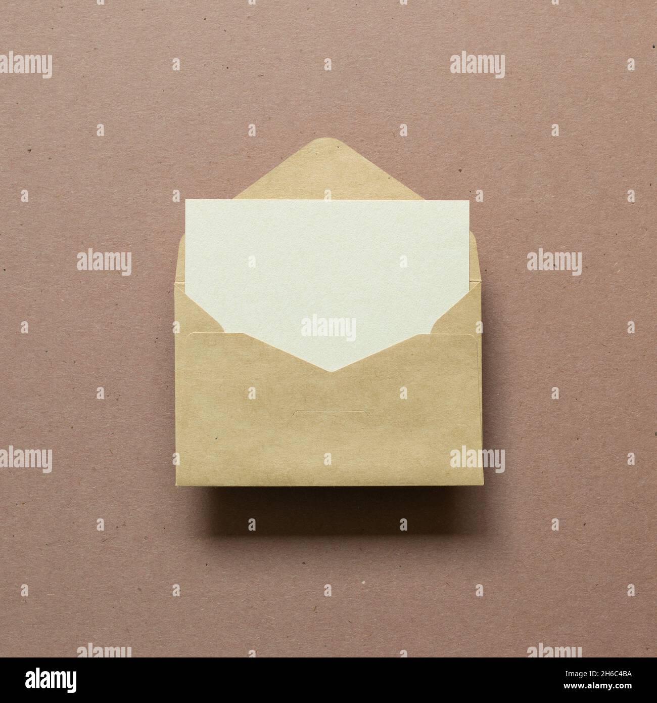 Blank card in kraft envelope on brown background. top view, copy space Stock Photo