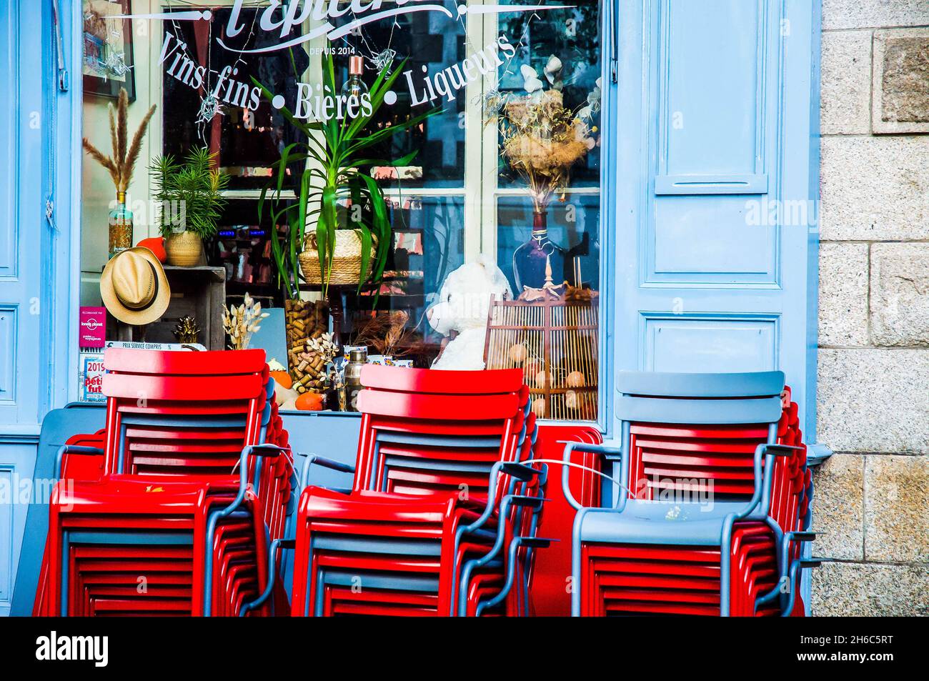 Postcard pretty exterior of a bar and cafe in Auray, Brittany, France. Red chairs against blue shutters. French lifestyle. Stock Photo