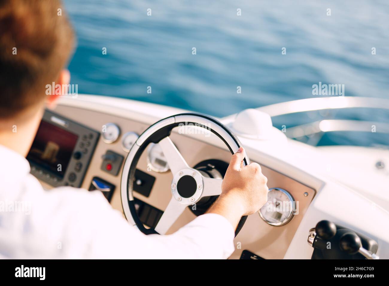 Man in a white shirt is driving a white motor boat. Closeup Stock