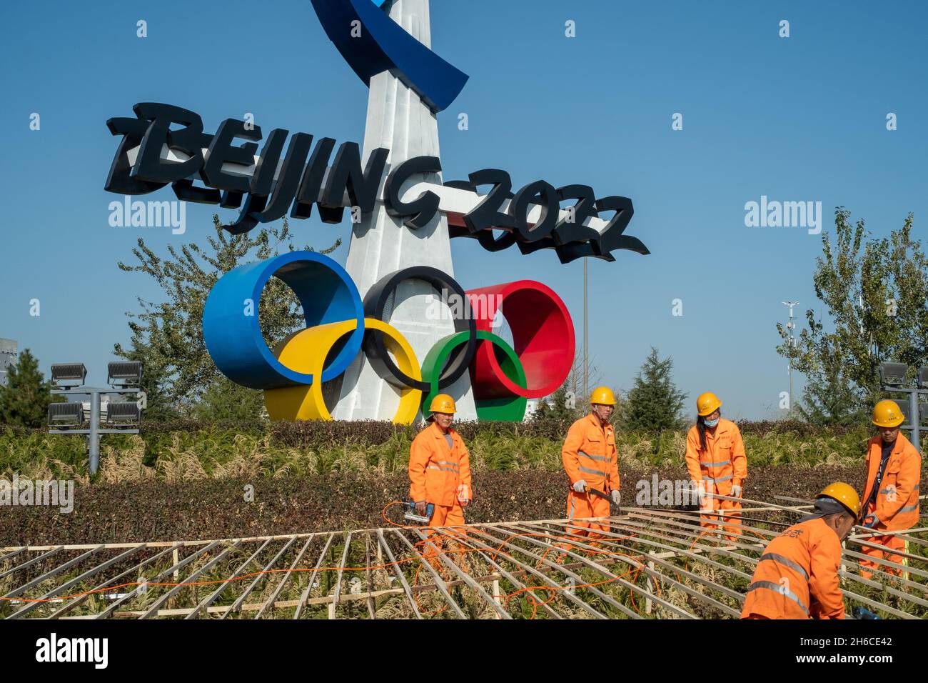 Urban ecological workers work in front of a huge emblem of Beijing 2022 Winter Olympics in Beijing, China. 14-Nov-2021 Stock Photo