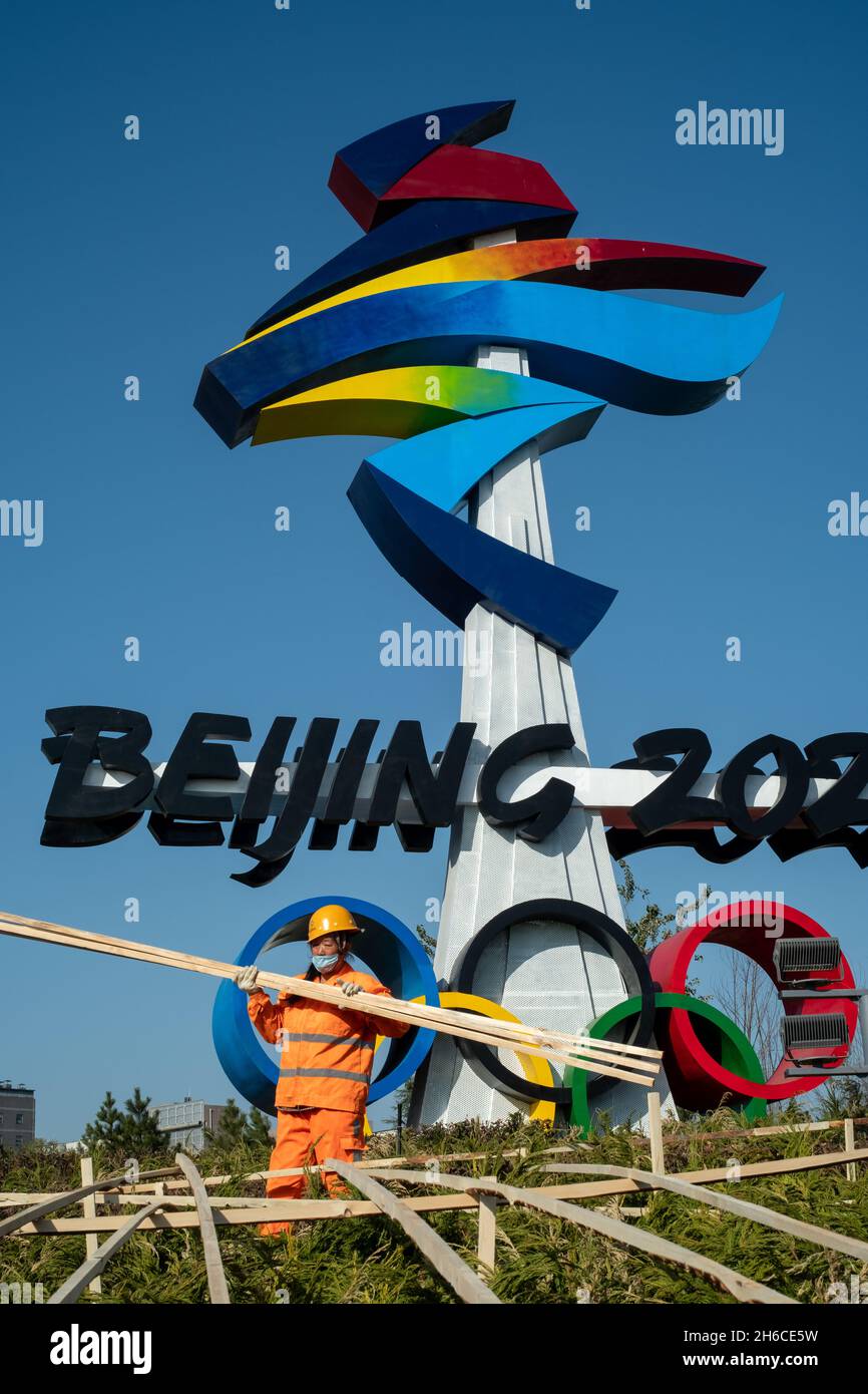 Urban ecological workers work in front of a huge emblem of Beijing 2022 Winter Olympics in Beijing, China. 14-Nov-2021 Stock Photo