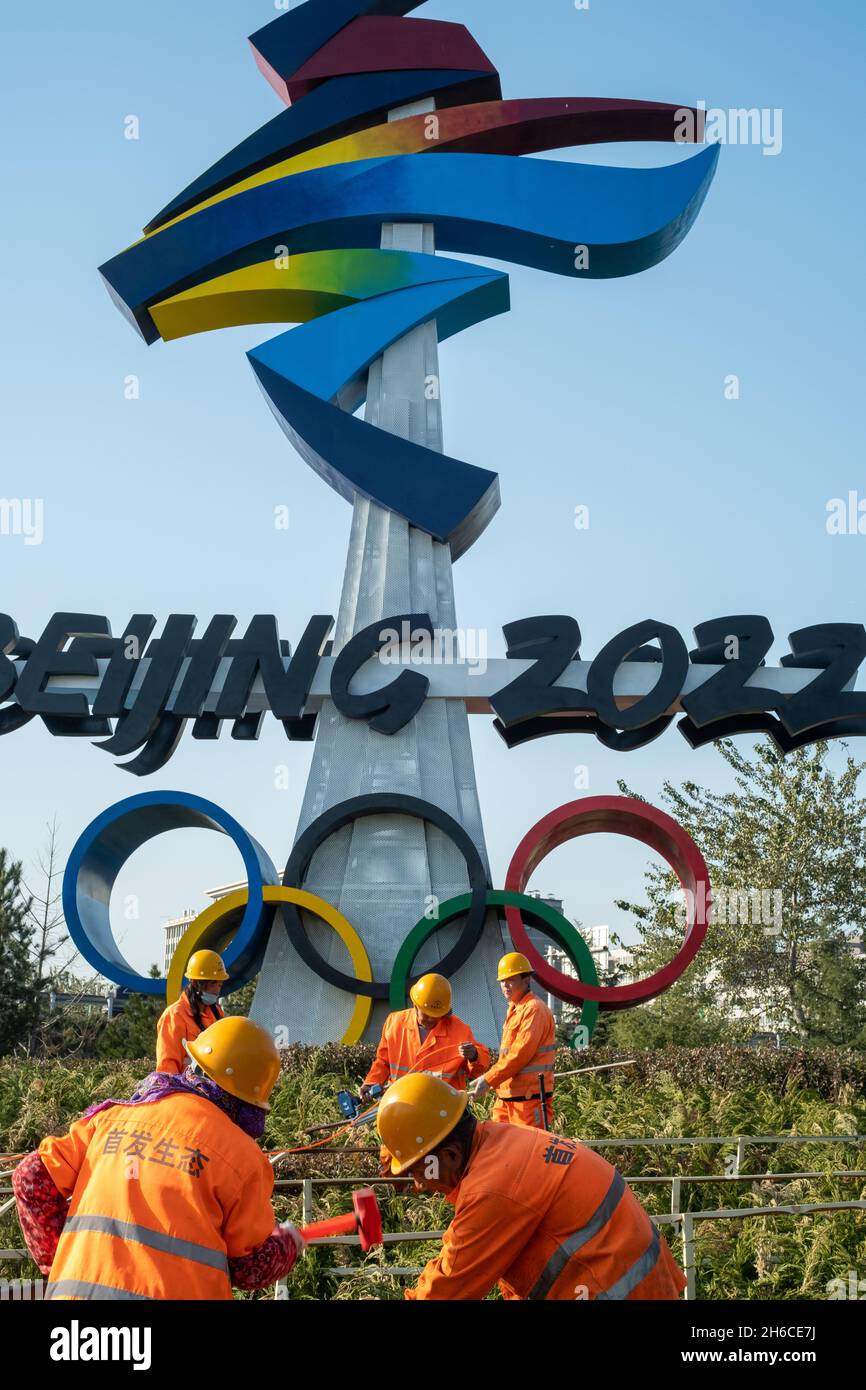 Urban ecological workers work in front of a huge emblem of Beijing 2022 Winter Olympics in Beijing, China. 14-Nov-2021 Stock Photo