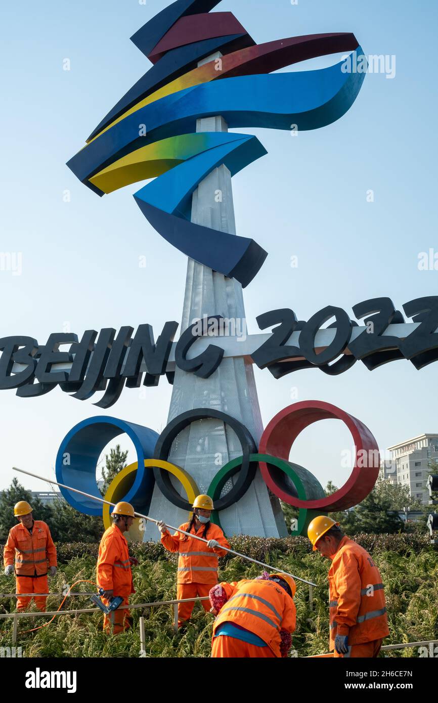 Urban ecological workers work in front of a huge emblem of Beijing 2022 Winter Olympics in Beijing, China. 14-Nov-2021 Stock Photo