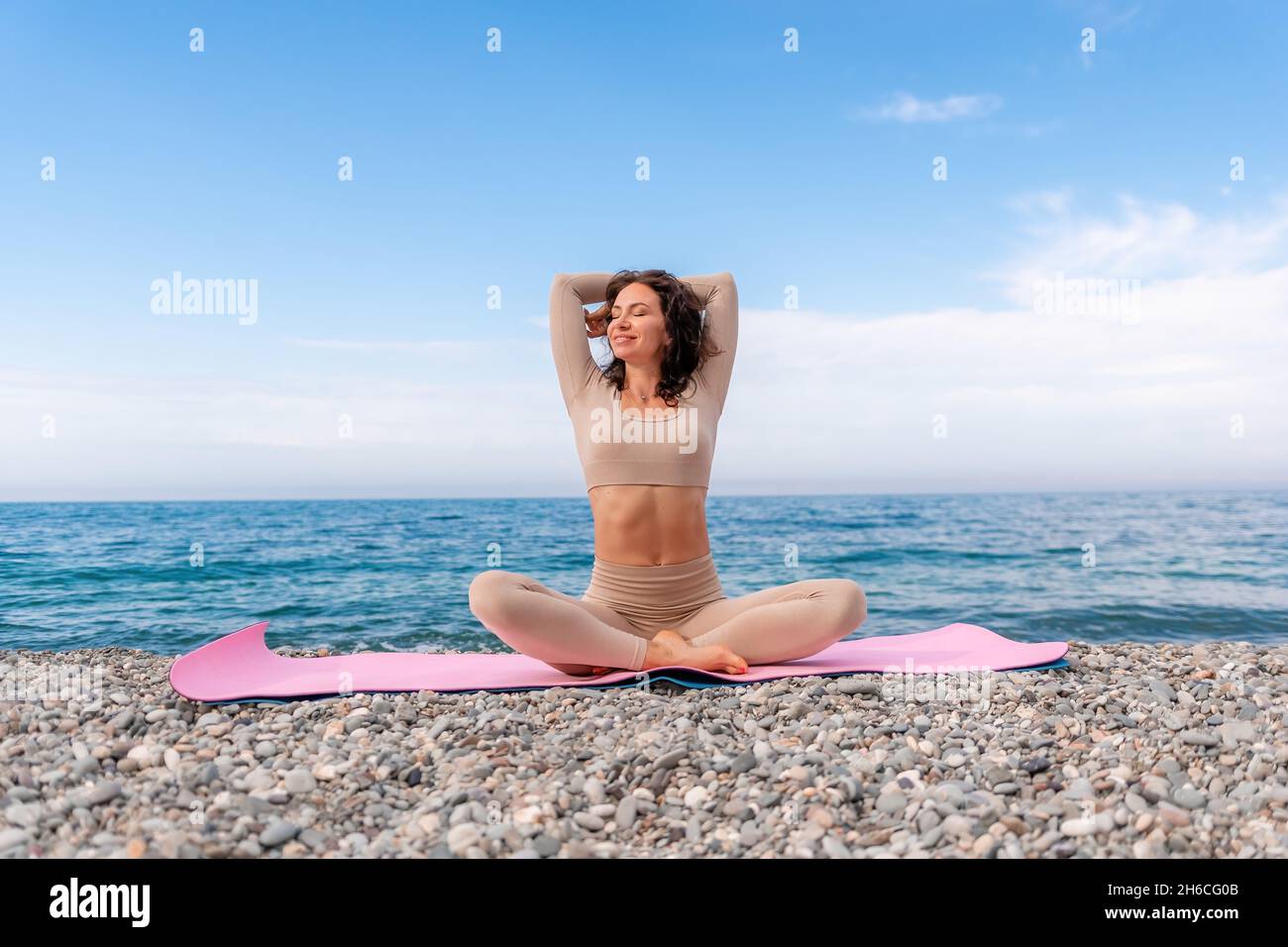Pregnant woman on the beach doing yoga. Pregnant woman doing prasarita  padhottanasana.Pregnant woman doing workout near the the sea. Stock Photo