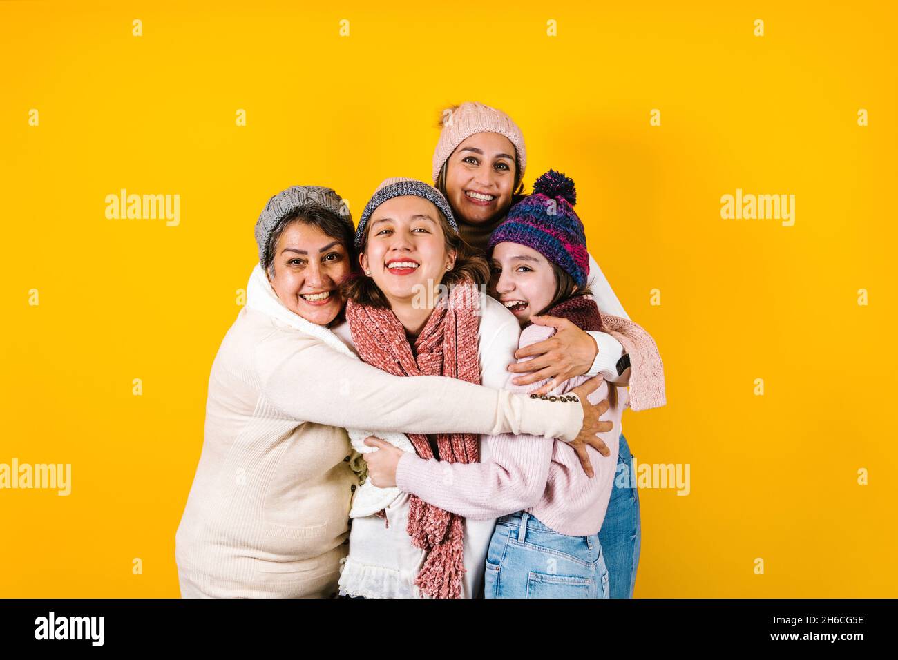 Winter portrait of happy latin family three generations of hispanic women on yellow background