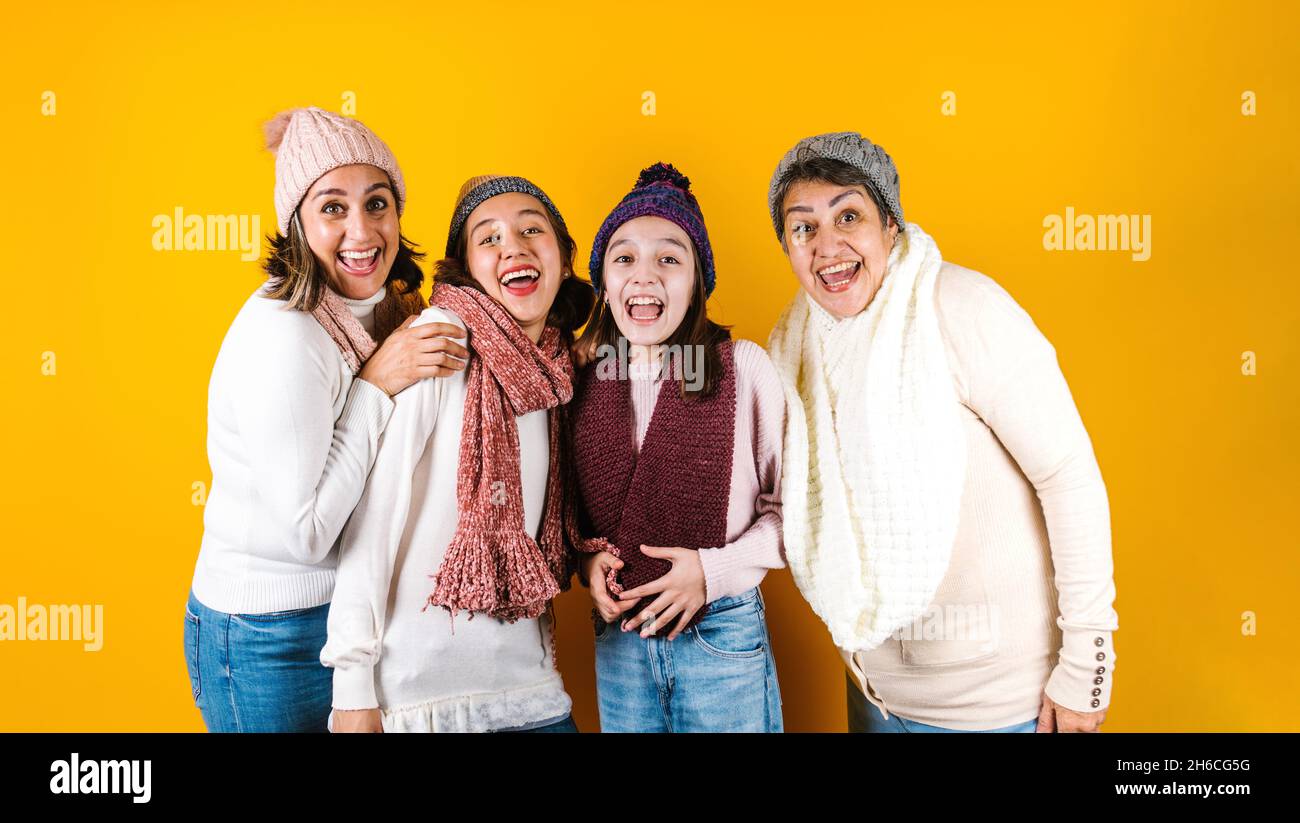 Winter portrait of happy latin family three generations of hispanic women on yellow background