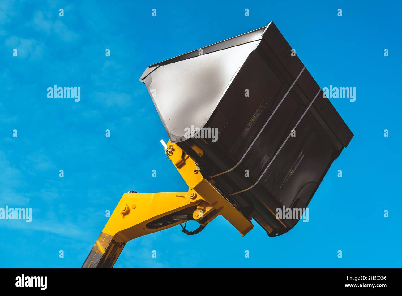 Excavator clean-up bucket or scoop against blue sky Stock Photo