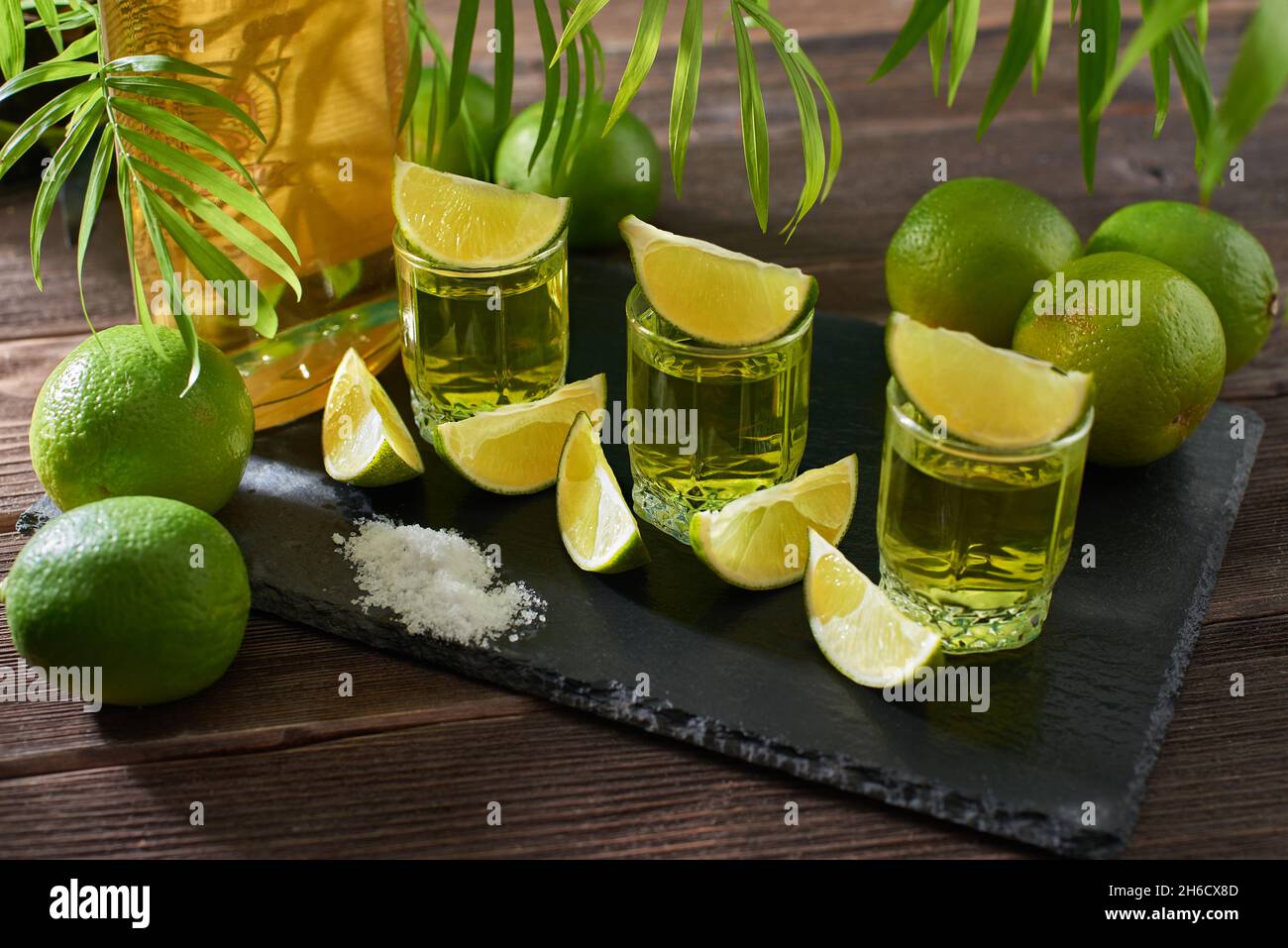 Bottle and glasses of tequila with lime on a wooden table. Traditional Mexican alcoholic beverage. Alcoholic cocktail with lime. The gin drink is serv Stock Photo
