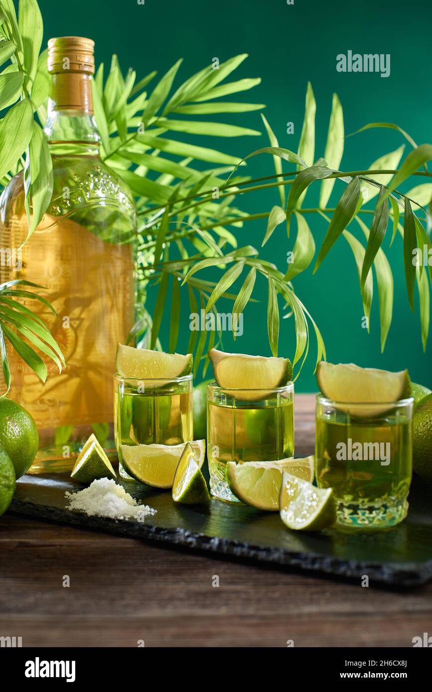 Bottle and glasses of tequila with lime on a wooden table. Traditional Mexican alcoholic beverage. Alcoholic cocktail with lime. The gin drink is serv Stock Photo