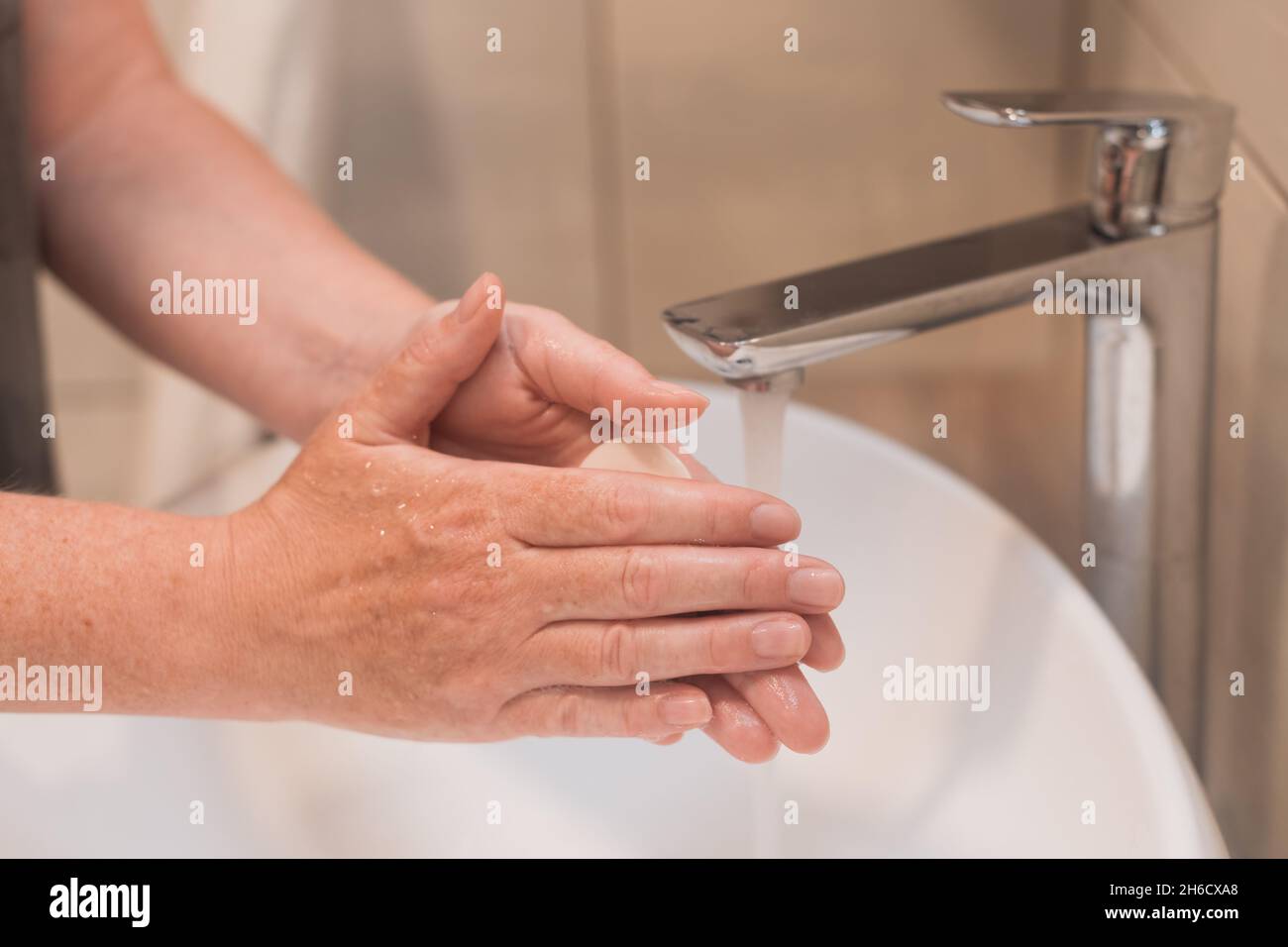 Close up of female washing hands with soap in bathroom, selective focus Stock Photo