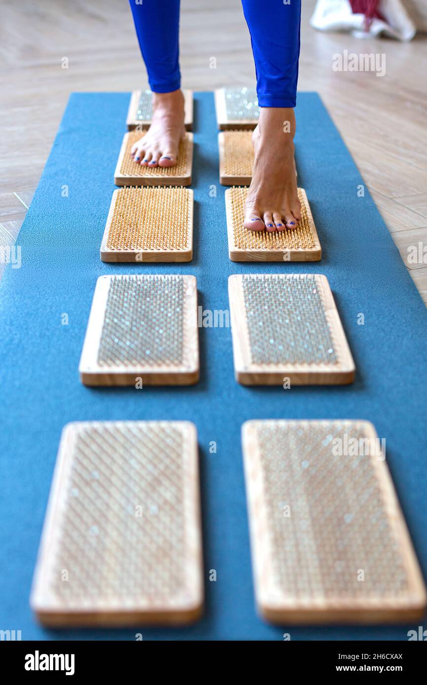Woman walking on a board with sharp nails over white background. Sadhu's board - practice yoga. Pain, trials, health, relaxation, cognition. Vertical Stock Photo