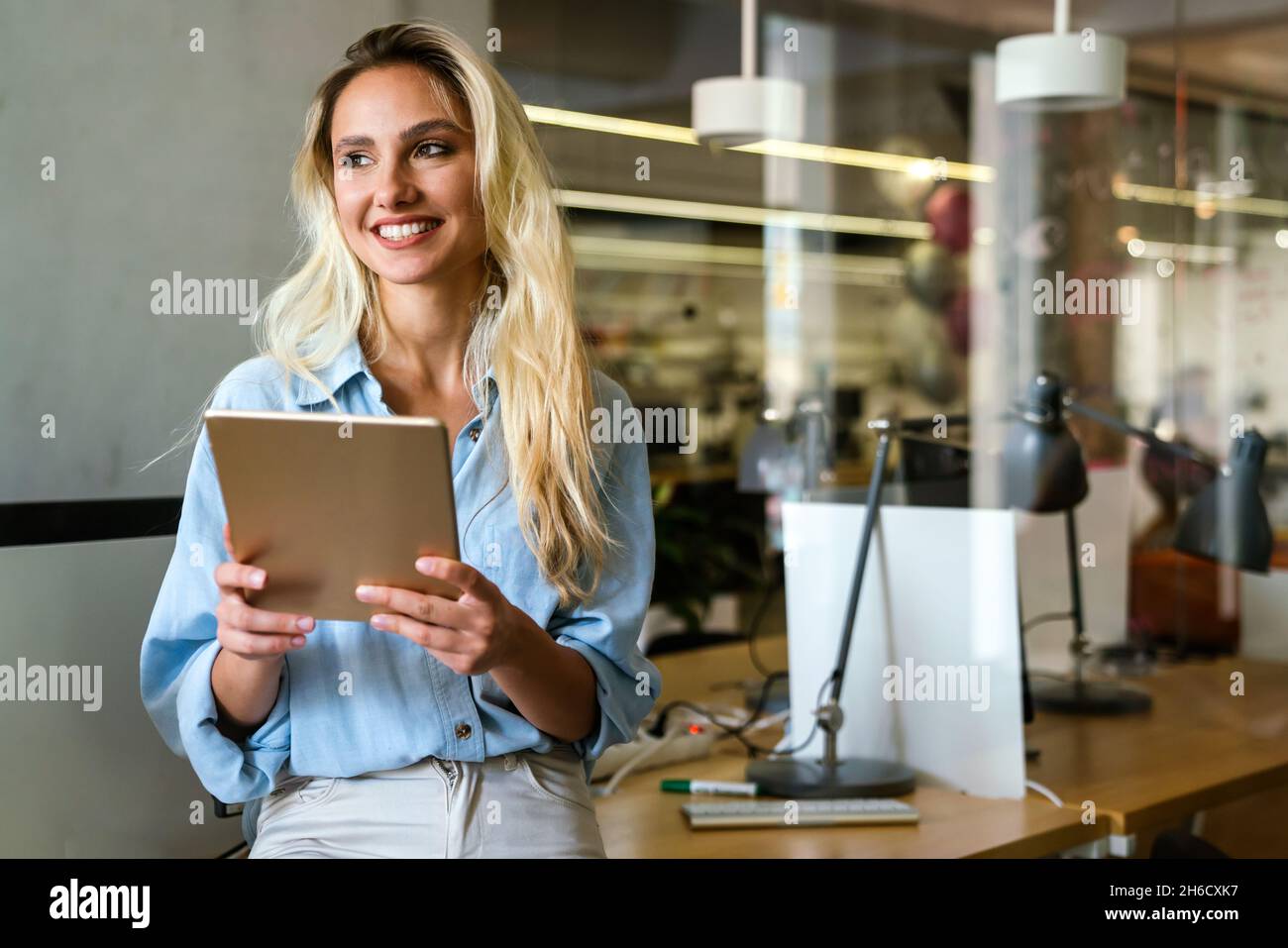 Portrait of happy successful woman working, websurfing on digital tablet in office Stock Photo