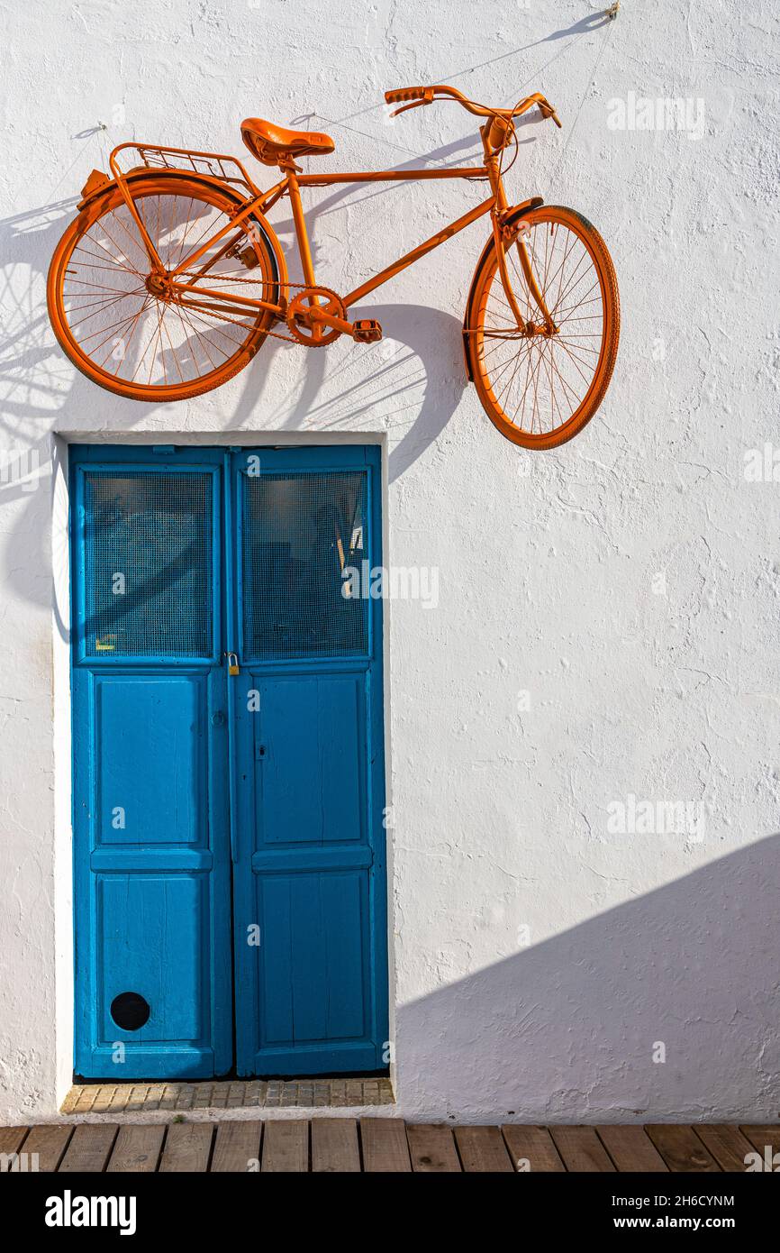 Orange bicycle hanging on a wall above a blue door Stock Photo Alamy