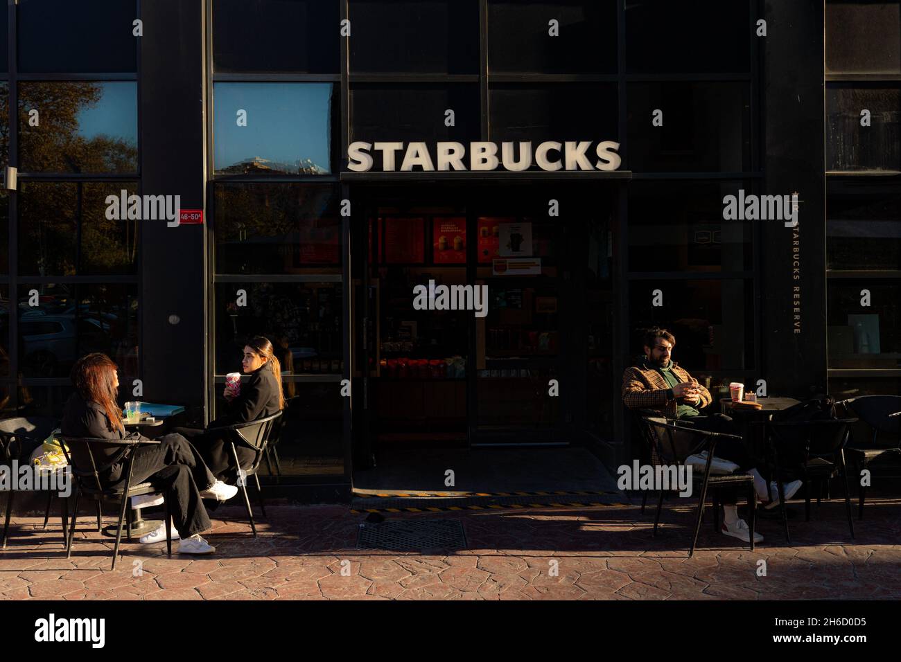 Istanbul, Turkey-Nov.12, 2021: People sit outside and enjoy the sunny weather while they are drinking their coffee in Karakoy, Istanbul. Stock Photo
