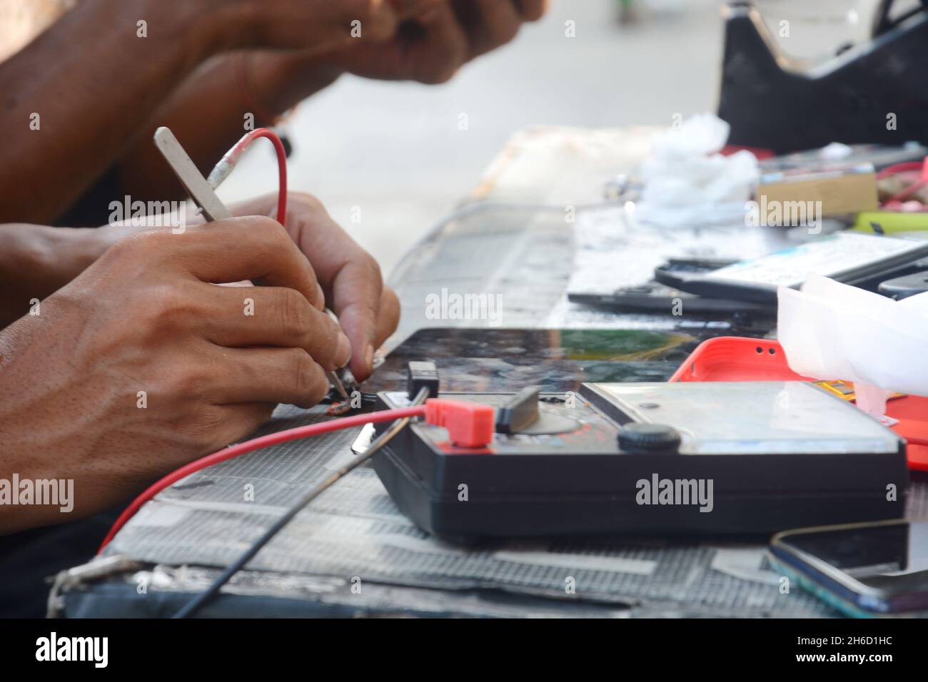 a technician is checking a cellphone using an avo meter Stock Photo