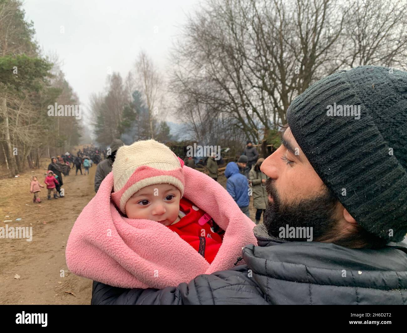 Grodno. 14th Nov, 2021. A refugee carries an infant at a refugee camp near the Belarusian-Polish border in Belarus, Nov. 14, 2021. Belarusian President Alexander Lukashenko ordered on Nov. 13 to set up tents and distribute relief supplies to refugees gathered near the Belarusian-Polish border. Credit: Henadz Zhinkov/Xinhua/Alamy Live News Stock Photo