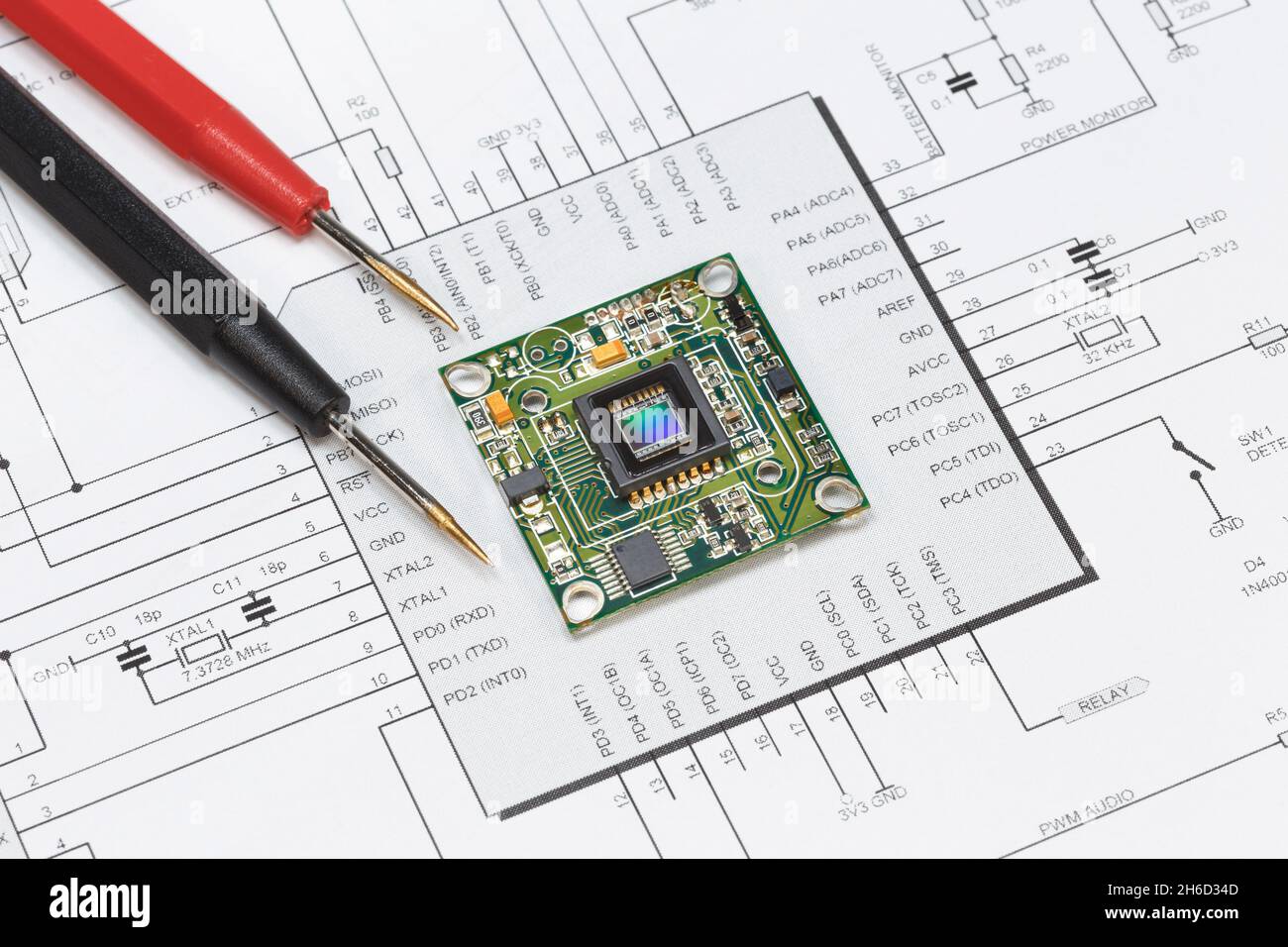 The module with the image sensor lies on the circuit diagram next to the tester probes. The concept of debugging, repairing electronic equipment Stock Photo