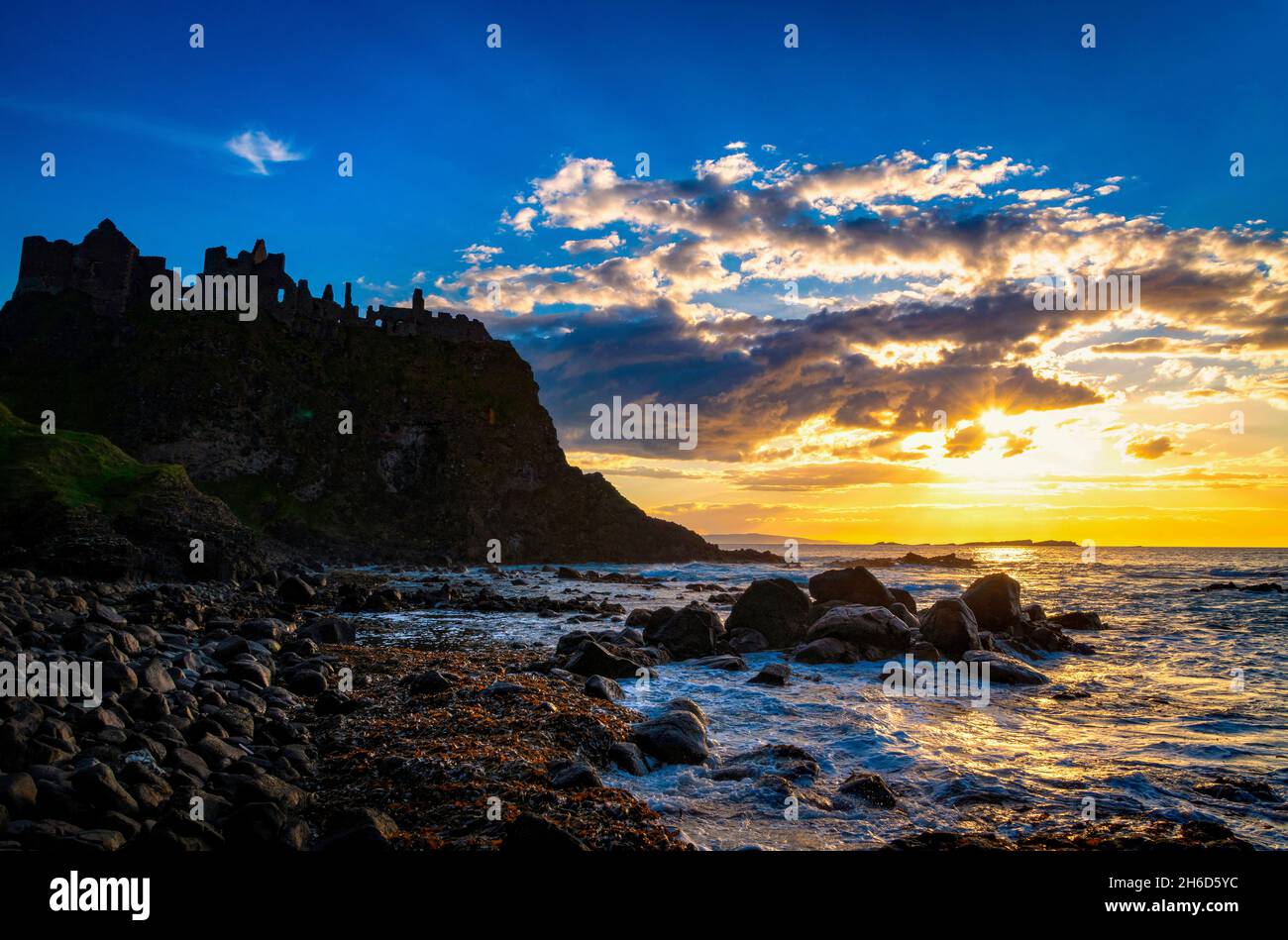 Ruins of Dunluce castle silhouetted by the sunsetting on the Irish coast Stock Photo