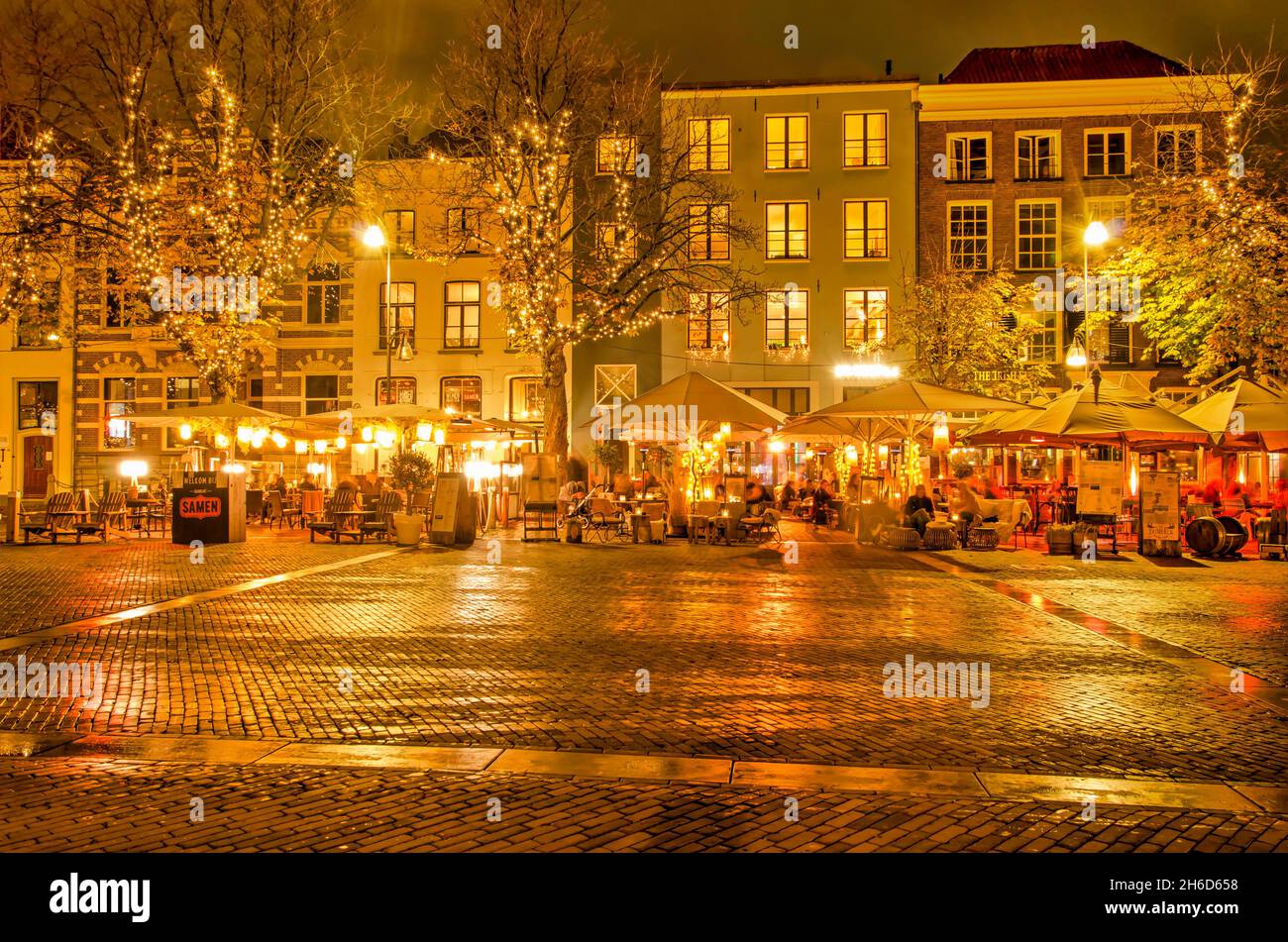 Deventer, The Netherlands, November 13, 2021: historic buildings and outdoor cafes on Brink square after dark Stock Photo