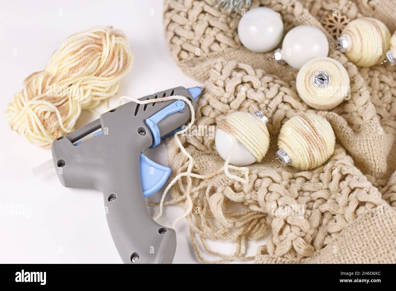 DIY boho style Christmas bauble ornaments with with cream colored cord attached to balls with hot glue gun Stock Photo