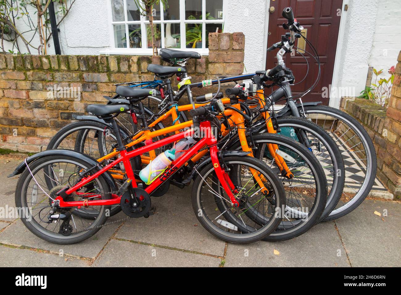 Four bicycles bikes 4 cycles locked sales outside the home of a cycling bike riding family. The cycle lock is attached to the garden wall. UK 127 Stock Photo Alamy