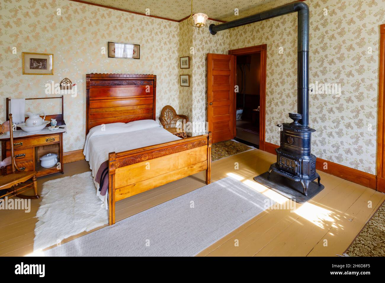 Traditional 19th century bedroom and wooden double bed and iron stove in the museum at Billings Farm & Museum, Woodstock, Vermont, New England, USA Stock Photo