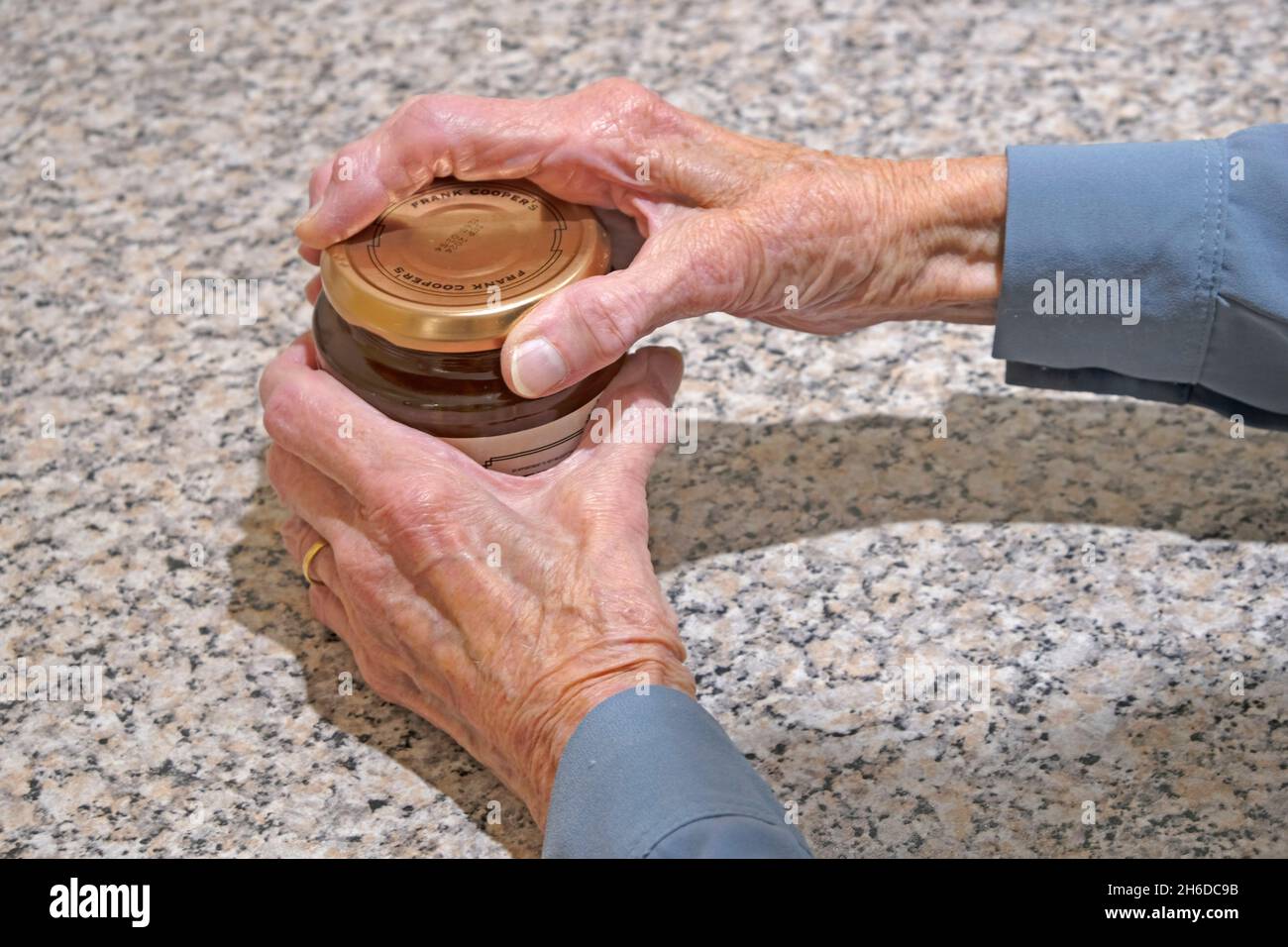 Senior lady opening a jam jar showing her ageing hands Stock Photo